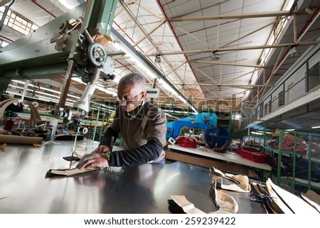 CAPE TOWN, SOUTH AFRICA - AUG 2: A man cuts fabric for a new garment in a large clothing factory in Cape Town, South Africa on August 2, 2012