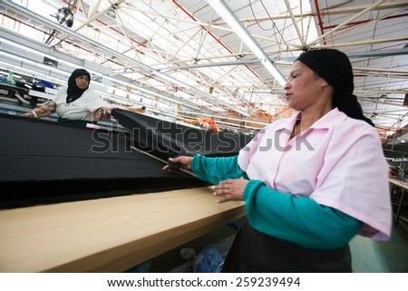 CAPE TOWN, SOUTH AFRICA - AUG 2: Women measure fabric for new garments in a large clothing factory in Cape Town, South Africa on August 2, 2012