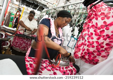 CAPE TOWN, SOUTH AFRICA - AUG 2: A woman irons a new garment in a large clothing factory in Cape Town, South Africa on August 2, 2012