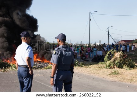 CAPE TOWN, SOUTH AFRICA - JANUARY 31: Police stand by as a large group of people protest against poor service delivery, in Cape Town, South Africa on January 31, 2012