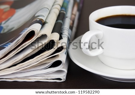 Take a break: pile of newspapers and cup of coffee on the table
