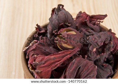 Dry hibiscus tea flowers in wooden bowl close up