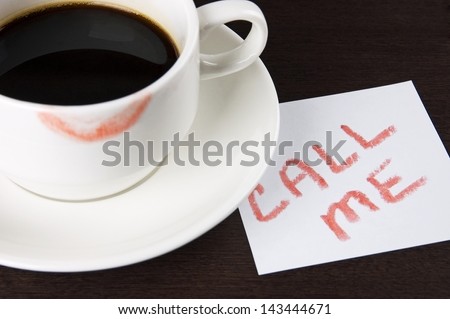 Cup of coffee with lipstick mark and note 'Call me' on table close up