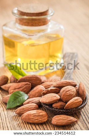 Bottle almond oil and almond on wood background