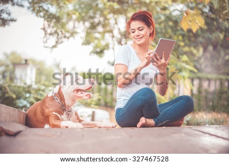 Woman with dog and holding a tablet.