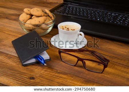 computer a cup of coffee and cookies on wooden table