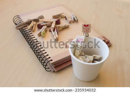 wooden clip set for paper clip in mini cup and paper clip put on notebook, concept of Romantic and in love, focus to the red wooden clip