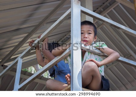 TAK, THAILAND - DECEMBER 26, 2014: A little boy tour guide is waiting service advise tourist in Hin Giw temple (wat phra that hin giw) at Tak, Thailand on 26 December, 2014.