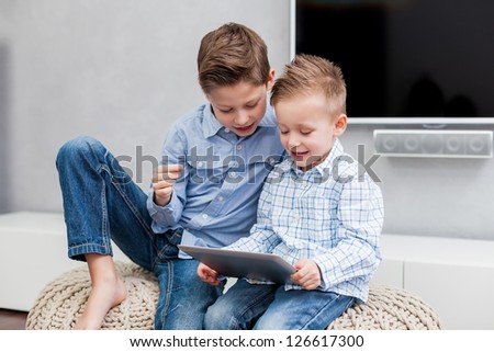 Two boys sitting in the living room using a tablet pc Two boys sitting in the living room using a tablet pc