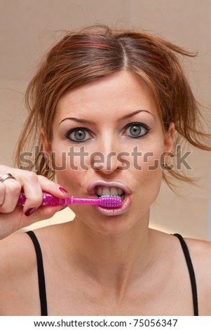 Young female brushing teeth looking funny
