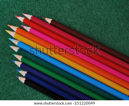 set of multicolored pencils on green texture background