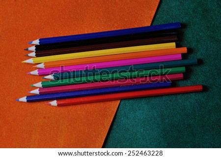 multicolored pencils on orange and green abstract textured background