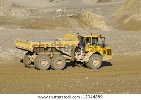 A yellow dump truck is driving in a mine