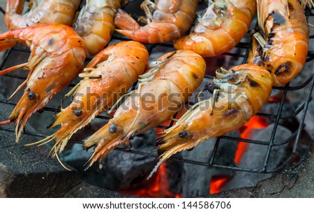 Grilled prawns on flaming grill.