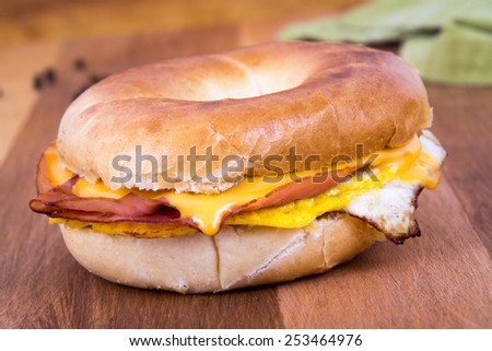 Ham, Egg and Cheese Breakfast Sandwich on a Bagel over a wood table
