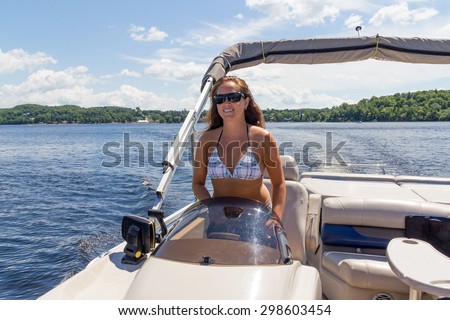 smiling women driving a pontoon boat on a lake at summer