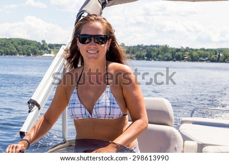 smiling women driving a pontoon boat on a lake at summer