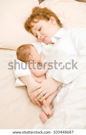 A newborn baby boy to breastfeeding. Young beautiful mother hugging him. Happy family.