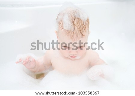 Cute baby is washing her hair in bath. The symbol of purity and hygiene education