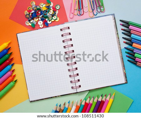 School, office, or artistic accessories - open notebook, colored paper, colored pencils, markers, paper clips, buttons. Ready for your logo, text or symbol.
