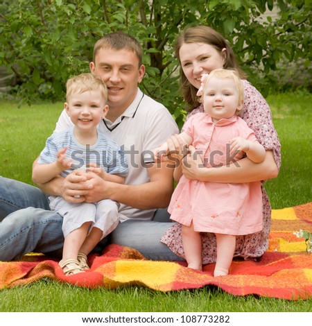 Happy family - father, mother, son, baby daughter on the grassy lawn.