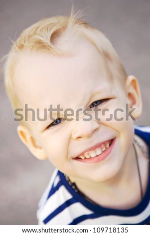 Portrait of a smiling little boy with blond hair and blue eyes close up. Taken from the top.