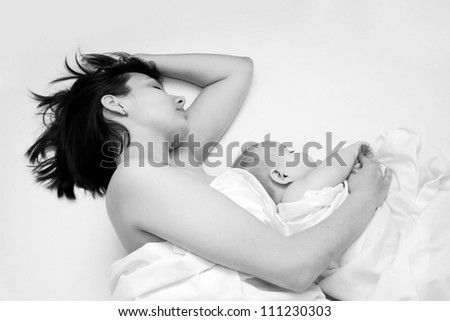 Black and white portrait - young mother and her baby sleeping in bed. Peaceful happy family life