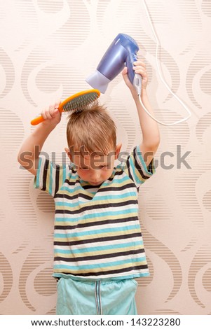 The little boy drying hair with  hair dryer.