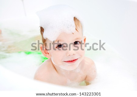 Happy boy in the bath, swimming in the foam. Baby shower.