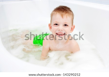 Little child swimming in the bath and smiling