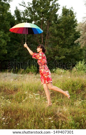 Middle-aged woman flying up with colorful umbrella