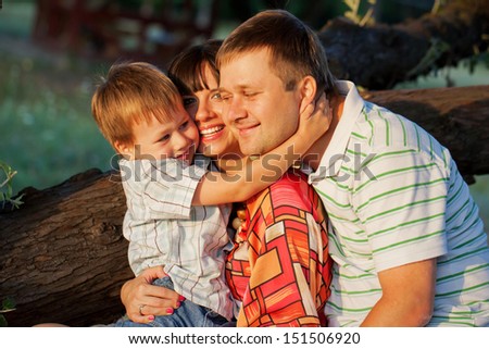 Happy family concept. Father, mother and son hugging in the park. Summer holiday.