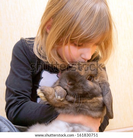 The little girl hugging and kissing rabbit. Love for animals concept.