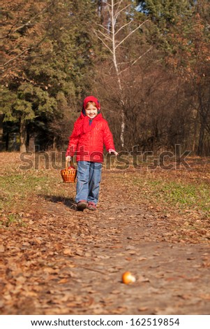 Happy smiling little girl with basket filled with mushrooms in the autumn forest. Harvest concept.