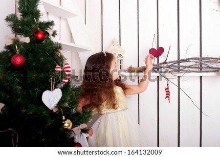 Happy elegant little girl climbing on ladder to decorate the Christmas tree and home. Christmas and New Year concept