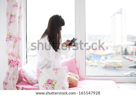 Young woman checking email and social networking accounts using tablet PC early in the morning. Modern technology and network concept.