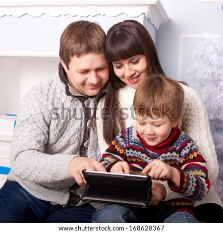 Happy family using the tablet. Funny father, mother and child, smiling family with tablet pc looking at something and laughing. Happy family concept.