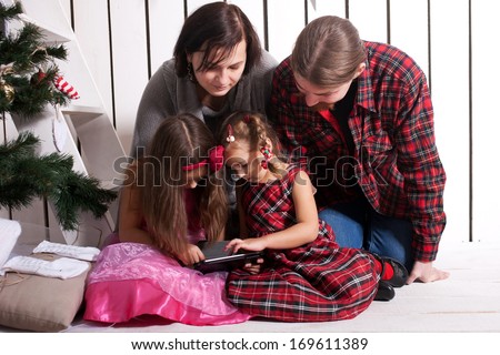Happy family using the tablet. Funny father, mother and children, smiling family with tablet pc looking at something and laughing. Happy family concept.