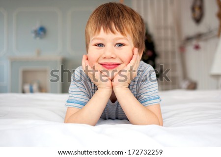 Little boy lying on the bed and smiling. Good morning!