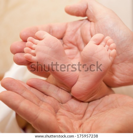 Newborn baby\'s feet in large hands of his father. Nursing, love and protection concept