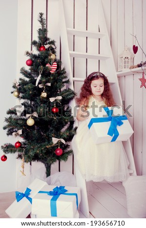 Happy smiling kid holding gifts near the Christmas tree. Christmas, New Year, holiday concept, ready for your text. Retro style.