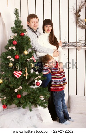 Happy family parents and kid near the Christmas tree. Christmas, New Year, holiday concept.