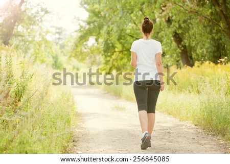 Runner woman jogging outdoors. Rear view. Healthy lifestyle and fitness concept.