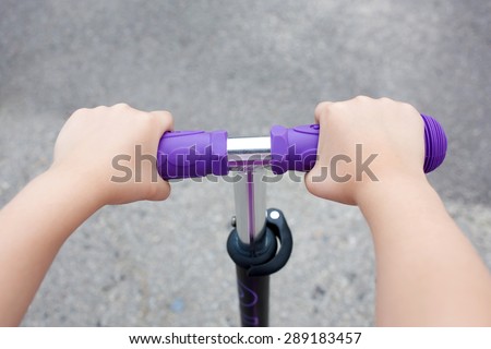 Kids hands holding handlebar on scooter or bicycle