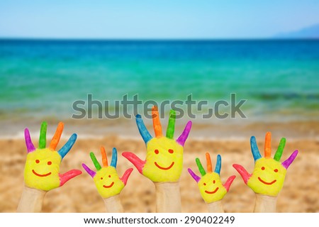 Smiley on hands against beach, sand, sea and sky background. Summer vacation and family freedom concept with copy space