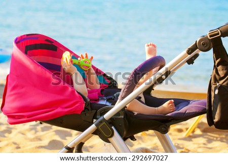 Baby lying in a stroller on the beach. Family holiday