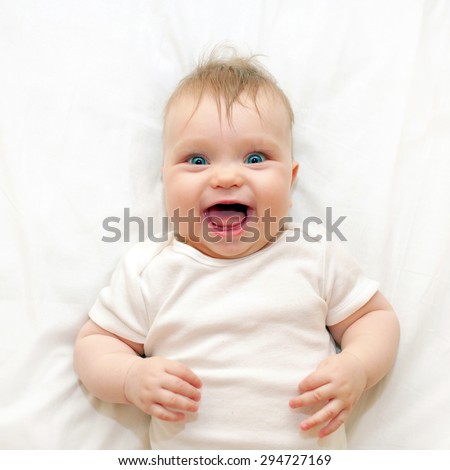 Smiling baby lying on a white bed. Good morning!