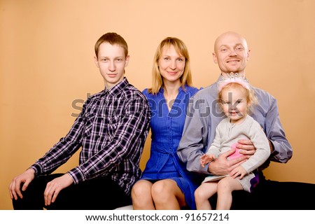 Happy family - middle aged father, mother, son and daughter. Isolated on a beige
