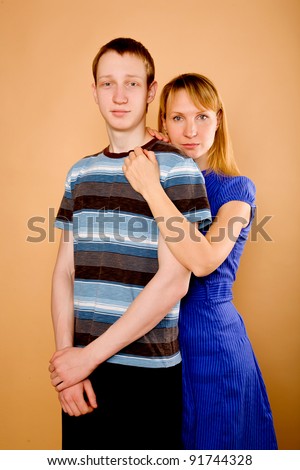 Portrait of middle aged mother and her adult son hugging isolated on beige background