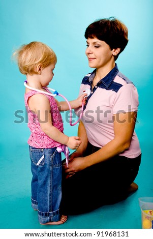 Mother and daughter playing doctor and patient. Isolated on turquoise